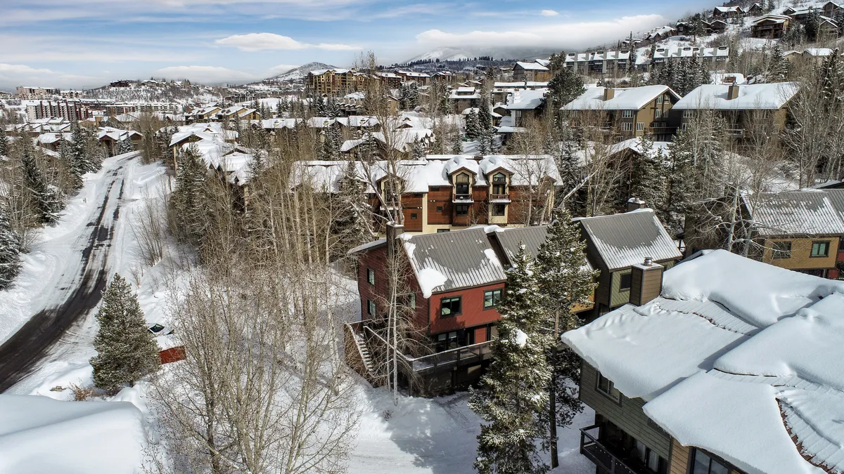 This exterior image showcases snow-covered rooftops, tree-lined streets, and distant mountains, capturing the quintessential Steamboat winter atmosphere. The scene exudes a cozy and inviting mood, hinting at the adventures awaiting just outside the door.